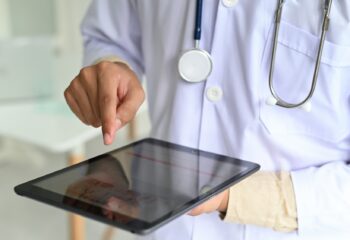medical-personnel-in-lab-gown-with-stethoscope-are-searching-for-medical-information-with-tablet-